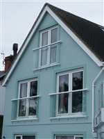White Juliet balconies on a pretty blue house
