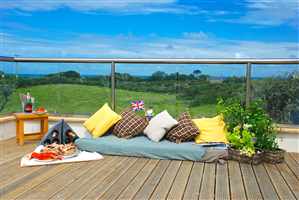 Countryside view from a straight Royal Chrome handrail balcony with cushions, plants and food