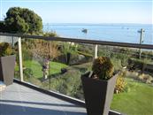 Lower maintencance and clear sea views are achieved by replacing an old wrought iron balcony with a glass and aluminium one from Balcony Systems.