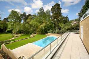 Long Royal Chrome balustrades over looking the blue swimming pool and garden