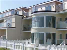 Silver Juliet balconies and balustrades on seafront residences surrounded by white picket fence