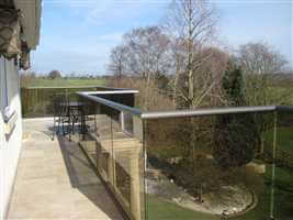 Wide zigzag balcony with bronze handrail and tinted glass looking over pretty views