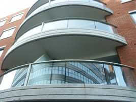 Curved balconies with silver handrails and posts on brick building