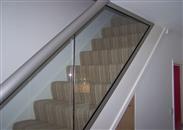 How does the use of glass handrails impact the perception of space within a home or building?