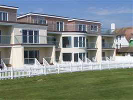 Silver Juliet balconies and balustrading surrounded by  white picket fence on the seafront
