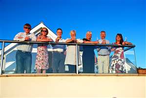 Family gathering on the balcony with clear glass and Royal Chrome handrails with the sun setting