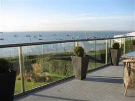Bronze aerofoil handrail with clear glass balcony looking over the sea covered in yatchs and boats