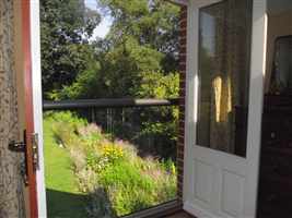 Looking out through a Bronze handrail Juliet balcony to a pretty garden