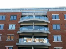 Curved silver balconies with privacy screens on brick building