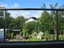 View of a colourful garden through clear glass balcony with Royal Chrome handrails
