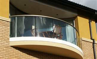 Curved semi frameless balcony with a Bronze handrail
