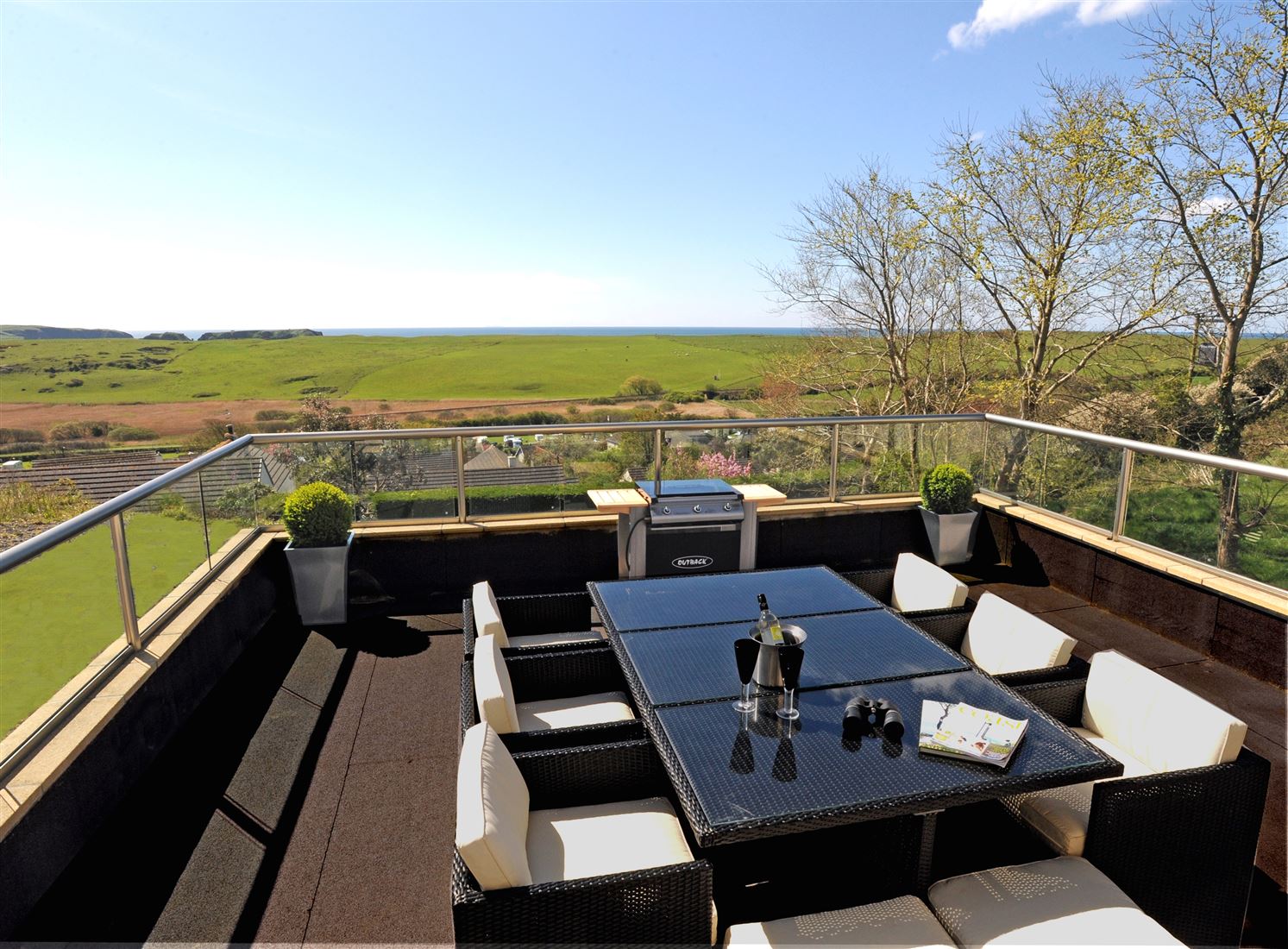 Table and chairs set-up on a Royal Chrome Orbit Glass Balustrade Balcony with stunning countryside views